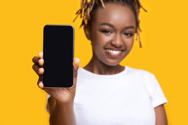 istock Cheerful black girl showing smartphone with blank screen 1272959281
