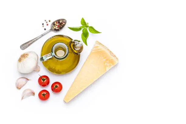 Italian food: Top view of some Italian ingredients like an olive oil bottle, basil, cherry tomatoes, parmesan cheese, garlic and pepper isolated on white background. Studio shot taken with Canon EOS 6D Mark II and Canon EF 24-105 mm f/4L