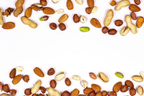 istock Top view of different nuts mix: almonds, pistachios, peanuts, hazelnuts as a horizontal frame isolated on white background 1272963627