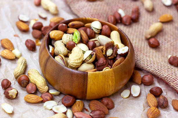 istock Different nuts: almonds, pistachios, peanuts, hazelnuts in wooden bowl on light background 1272963708