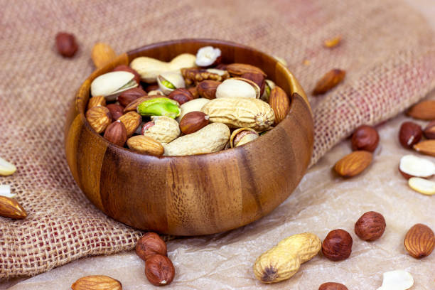 istock Different nuts: almonds, pistachios, peanuts, hazelnuts mix in wooden bowl on light background 1272963858