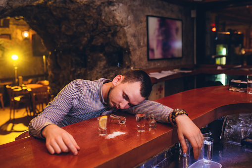 Young Caucasian man knock out on bar counter from alcohol.