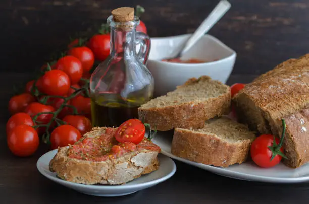 Photo of Popular Spanish breakfast. Crusty bread with fresh cherry tomato and olive oil is typical tapa  in Spain.