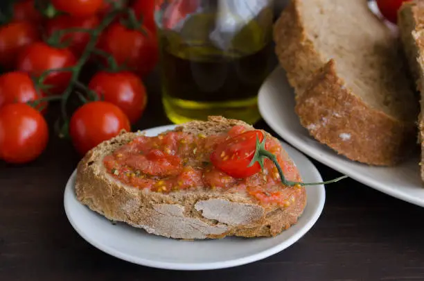 Photo of Popular Spanish breakfast. Crusty bread with fresh cherry tomato and olive oil is typical tapa  in Spain.Mediterranean diet cousine