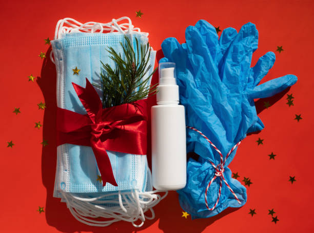 hygienic face masks antibacterial gel and medical gloves as a gift with a red ribbon, christmas and new year 2021 decor on a red background. holidays self-isolation and coronavirus pandemic concept - medicine cabinet medicine healthcare and medicine cabinet imagens e fotografias de stock