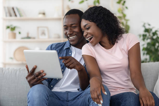 istock Cheerful black man and woman using digital tablet at home 1272973008