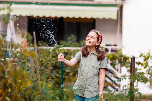 Cheerful girl working on organic garden.She watering and care for plants on her garden.