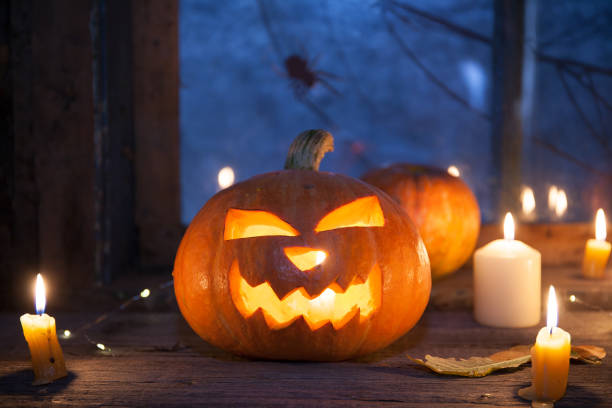 istock Halloween background, Jack-o ' - lantern pumpkins next to burning candles on night window background 1272975578