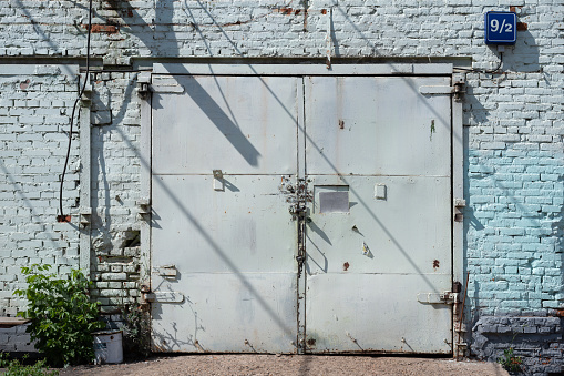 Old closed gray metal gates of a brick industrial building 9/2