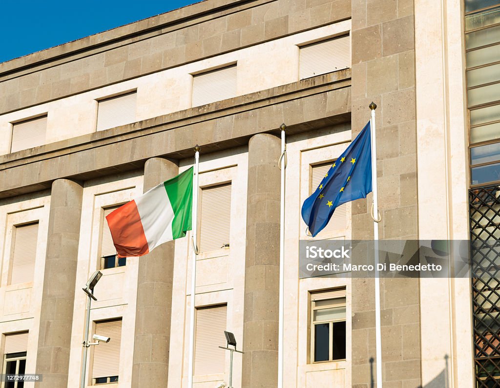 European Union EU and Italian Flags Together European Union EU and Italian Flags Together waving at wind outside a building Architecture Stock Photo