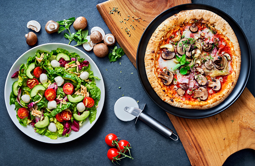 pizza and salat ready to eat on a stone undergound, with wooden board