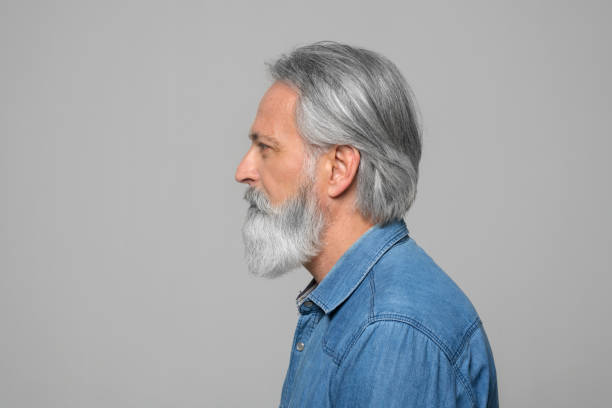 Side view of mature man Side view of mature man standing against grey background. 55 59 years photos stock pictures, royalty-free photos & images