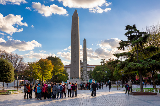 Istanbul, Turkey - Oct 25, 2018: Tourists near Obelisk of Theodosius, Egyptian obelisk of Pharaoh Thutmose III re-erected in Hippodrome of Constantinople by Roman emperor Theodosius I in the 4th century.