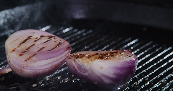 Fresh red onion is being fried on grill frying pan. Close-up