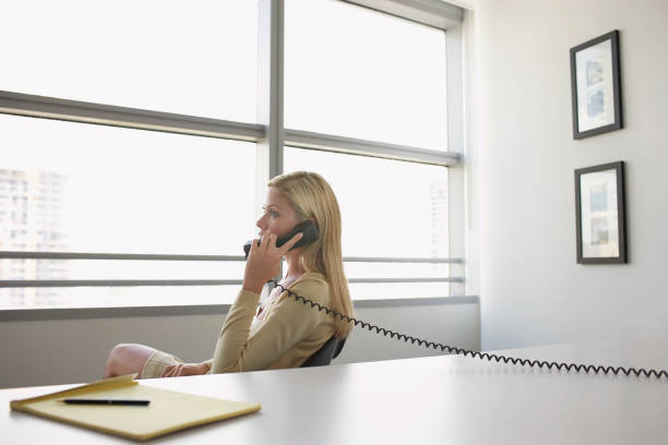 istock Business woman using phone sitting at office desk side view 1272979773