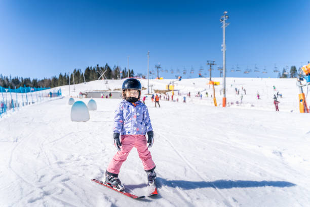 Young skier girl learning how to ski and having fun on ski slope stock photo