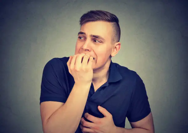 Photo of Anxious hesitant man biting his fingernails