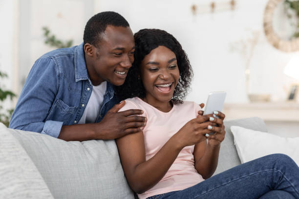 istock Joyful african couple playing game on smartphone 1272984959