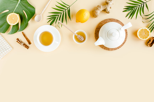 Herbal tea with mint, ginger, lemon, honey and other herbs on yellow background. Flat lay, top view