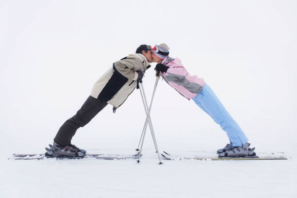 Couple leaning towards each other standing on skis side view