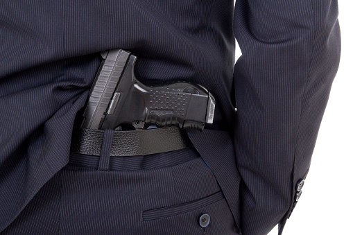 close up of gun in business suit pants isolated on white background