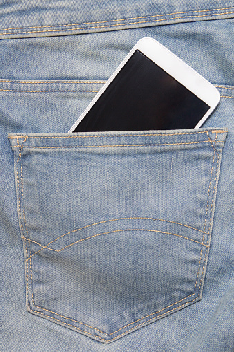 smartphone with blank screen in back pocket of blue jeans