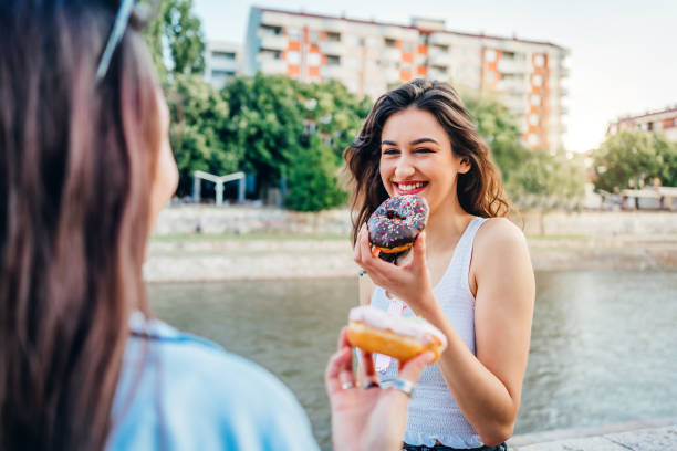 istock Two young women eating donuts 1272991838