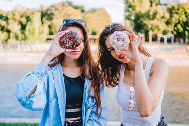 istock Women having fun with donuts 1272992289