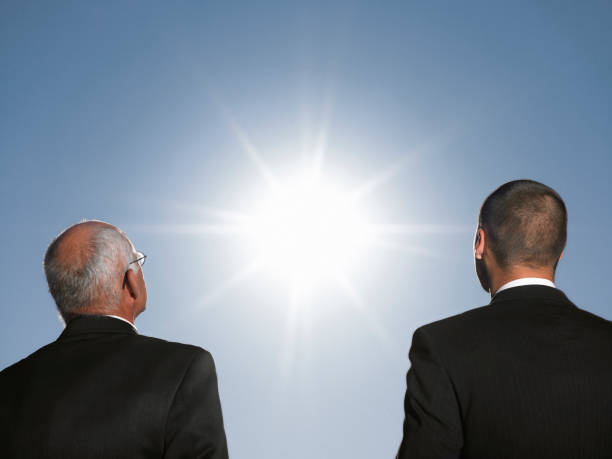 istock Businessmen looking at the sun head and shoulders back view 1272992310