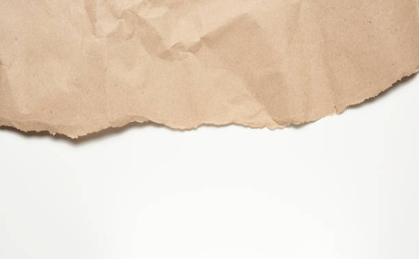 crumpled sheet of brown wrapping paper on a white background crumpled sheet of brown wrapping paper on a white background, backdrop for the designer, copy space torn brown paper stock pictures, royalty-free photos & images