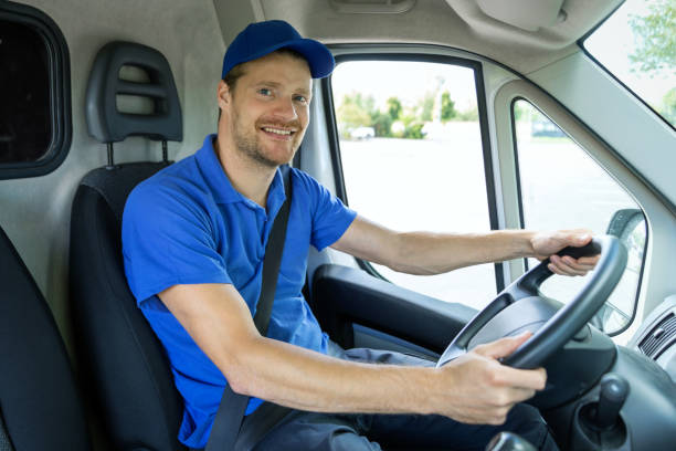 transportation services - young male driver in blue uniform driving a van. smiling at camera transportation services - young male driver in blue uniform driving a van. smiling at camera wheel cap stock pictures, royalty-free photos & images