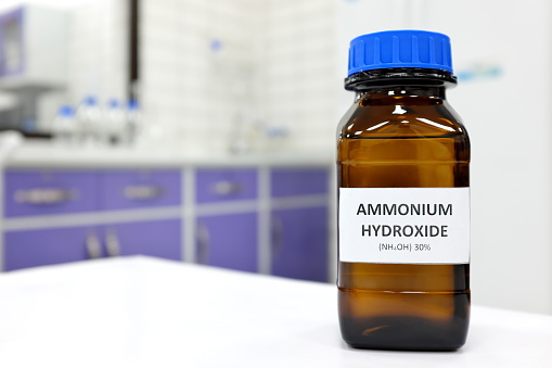 Selective focus of ammonium hydroxide or ammonia solution in glass amber bottle inside a chemistry laboratory with copy space.