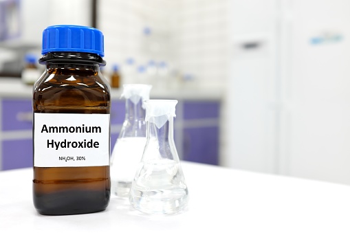 Selective focus of ammonium hydroxide or ammonia solution in glass amber bottle inside a chemistry laboratory with copy space.