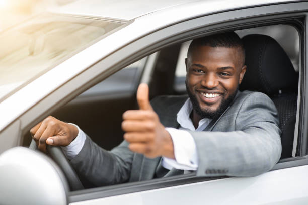 istock Happy black businessman looking through car window, showing thumb up 1273001366