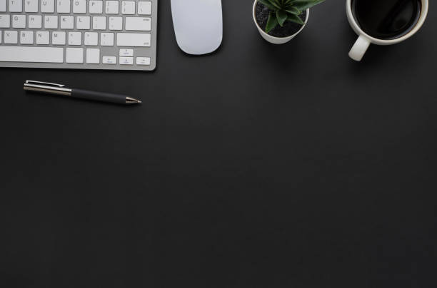 istock Top view above of Black office desk table with keyboard, mouse computer and coffee cup with equipment other office supplies. Business and finance concept. Workplace, Flat lay with blank copy space. 1273001687