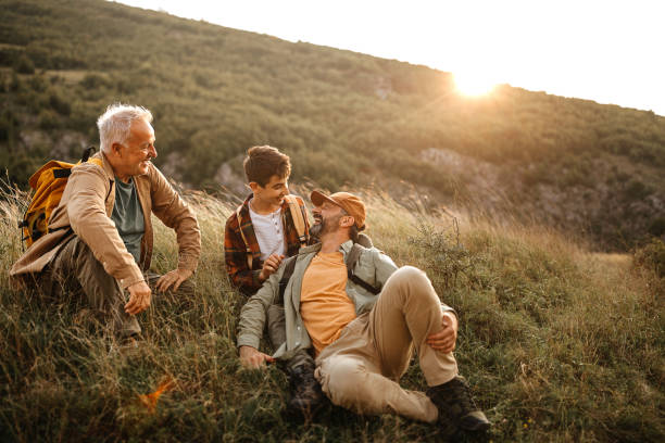 Happy three generations males relaxing on hiking tour Elderly father with adult son and grandson relaxing in nature during hiking tour picnic photos stock pictures, royalty-free photos & images