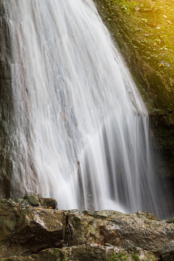 Close-up view of a stream of waterfalls flowing down from a rocky mountain in Thailand.