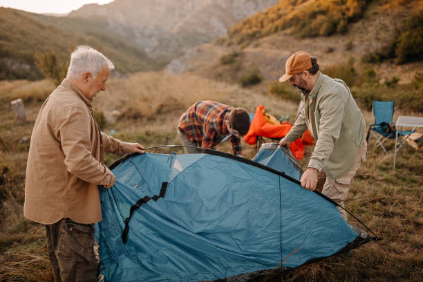 three generations males assembling tent on hill - camping tent offspring 60s imagens e fotografias de stock
