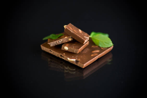 cioccolato fondente dolce con noci su sfondo nero - healthy eating eating food and drink beer nuts foto e immagini stock