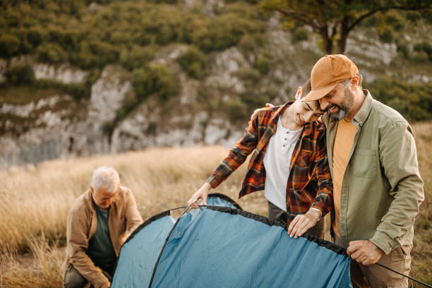 three generations males assembling tent on hill - camping tent offspring 60s imagens e fotografias de stock