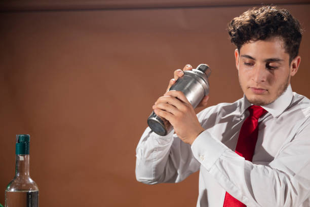 barman prepara una bevanda alcolica con uno shaker al bar con alcuni bicchieri di liquore. - shakerismo foto e immagini stock