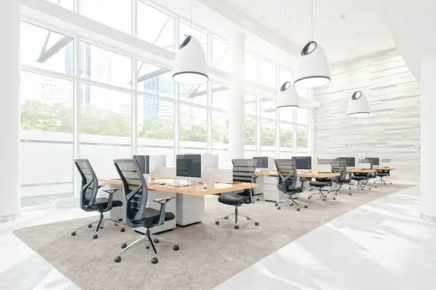 Interior of a modern empty office space with desks, computers and chairs.