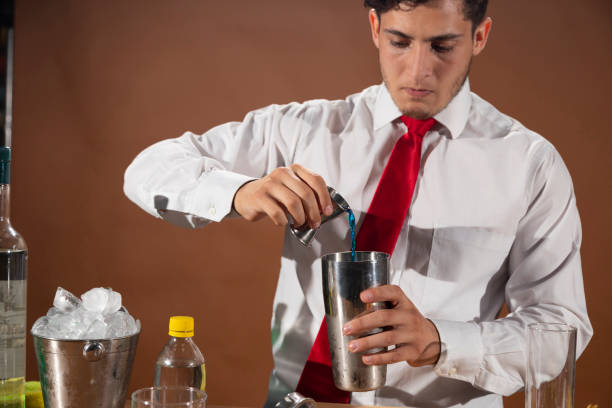 barman prepara una bevanda alcolica con uno shaker al bar con alcuni bicchieri di liquore. - shakerismo foto e immagini stock