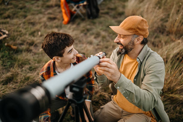 Father and son adjusting telescope on a picnic site