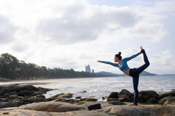 istock Asian woan practicing yoga outdoors on the beach with the blue sky background. 1273008475