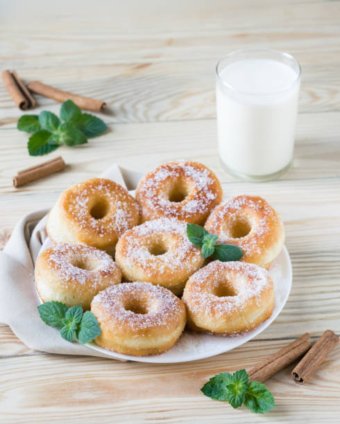istock Homemade ring-shaped sugared donuts on a white plate on a light wooden background, rustic style 1273008843