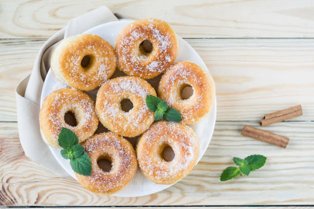 istock Homemade ring-shaped sugared donuts on a white plate on a light wooden background, rustic style 1273008847