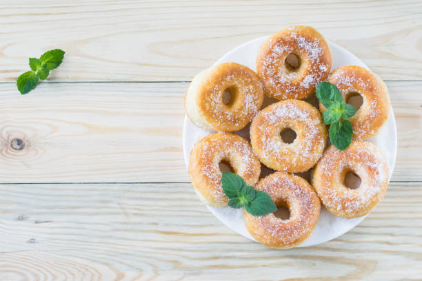 istock Homemade ring-shaped sugared donuts on a white plate on a light wooden background, rustic style, copy space, top view 1273008857