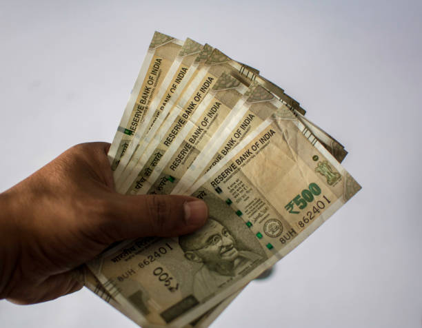 istock Indian Currency Holding by hand on white background 1273009135
