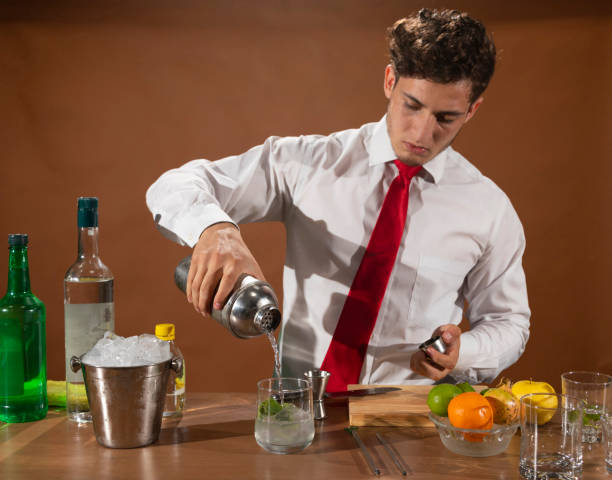 barman prepara una bevanda alcolica con uno shaker al bar con alcuni bicchieri di liquore. - shakerismo foto e immagini stock